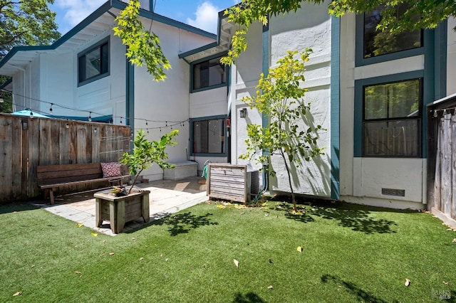 rear view of property featuring a patio, a lawn, and fence