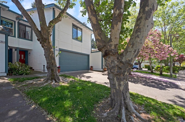 view of side of home featuring concrete driveway, stucco siding, and a garage
