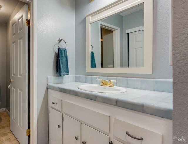 bathroom with vanity and a textured wall