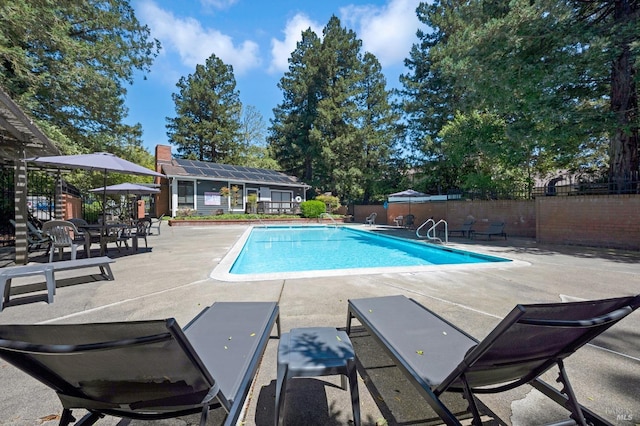 pool featuring fence, an outdoor structure, and a patio area