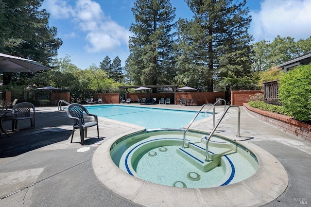 pool featuring a patio, a fenced backyard, and a community hot tub