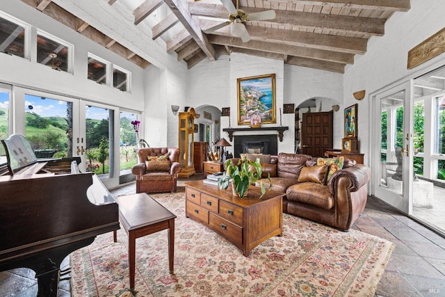 living area with high vaulted ceiling, plenty of natural light, french doors, and stone tile floors