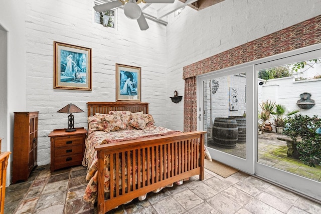 bedroom with stone tile flooring, ceiling fan, a high ceiling, and access to exterior