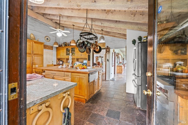 kitchen with beam ceiling, a center island, freestanding refrigerator, a warming drawer, and stone tile flooring