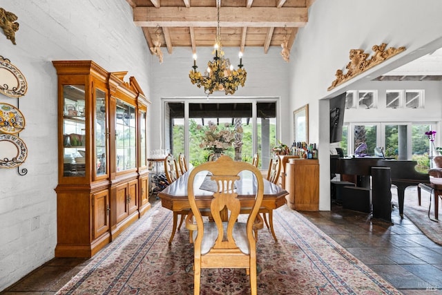 dining area featuring wood ceiling, beamed ceiling, a notable chandelier, a high ceiling, and stone tile floors