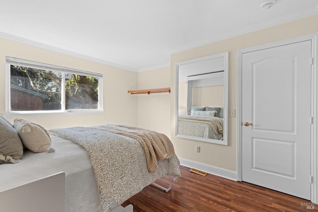 bedroom featuring crown molding, baseboards, visible vents, and wood finished floors