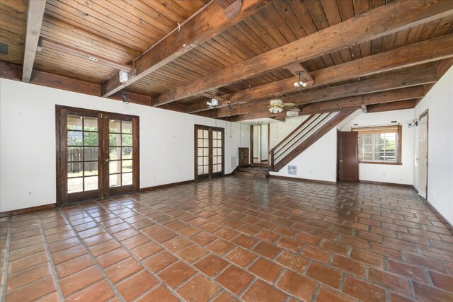 unfurnished living room featuring beam ceiling, french doors, baseboards, a healthy amount of sunlight, and wood ceiling