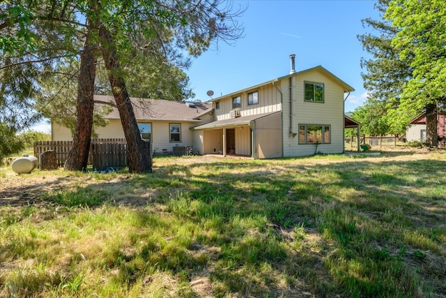 rear view of house with central AC unit, board and batten siding, and fence
