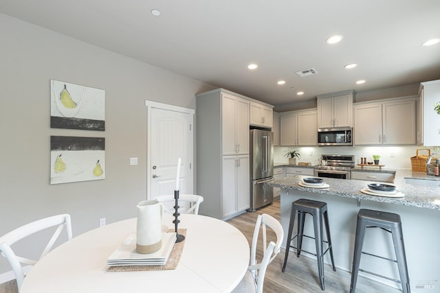 kitchen with a breakfast bar area, visible vents, appliances with stainless steel finishes, a peninsula, and light wood-style flooring