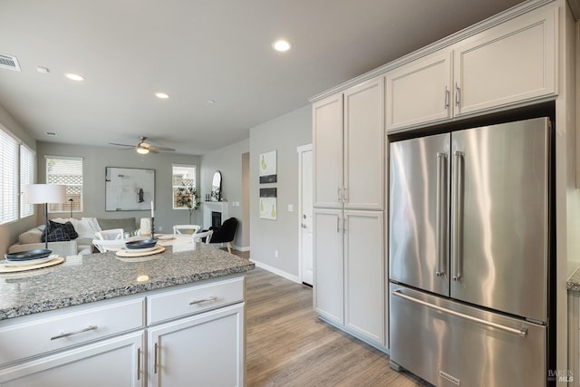 kitchen featuring ceiling fan, light stone countertops, light wood-style flooring, high end refrigerator, and recessed lighting