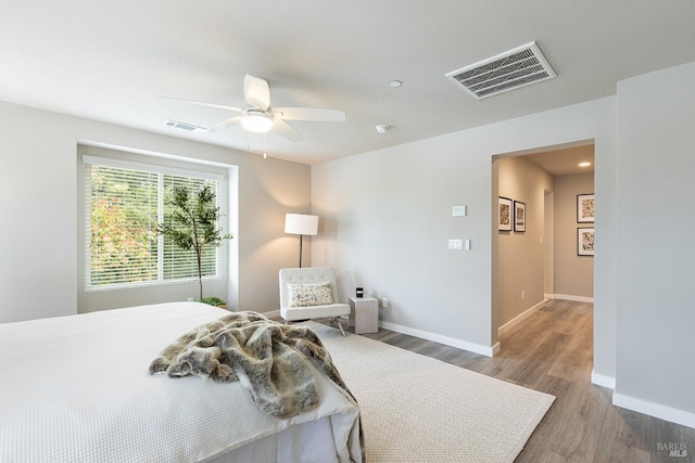 bedroom with baseboards, a ceiling fan, wood finished floors, and visible vents
