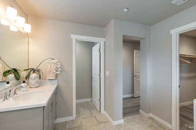 bathroom with vanity, baseboards, a spacious closet, and visible vents