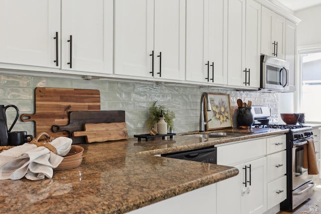 kitchen featuring white cabinets, appliances with stainless steel finishes, a sink, dark stone counters, and tasteful backsplash