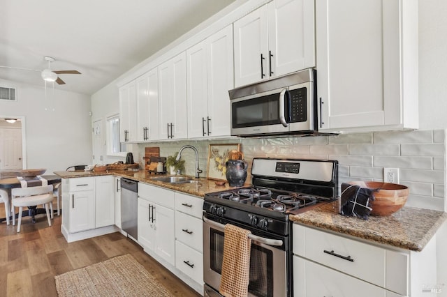 kitchen with a ceiling fan, white cabinetry, a sink, stainless steel appliances, and light wood-style flooring