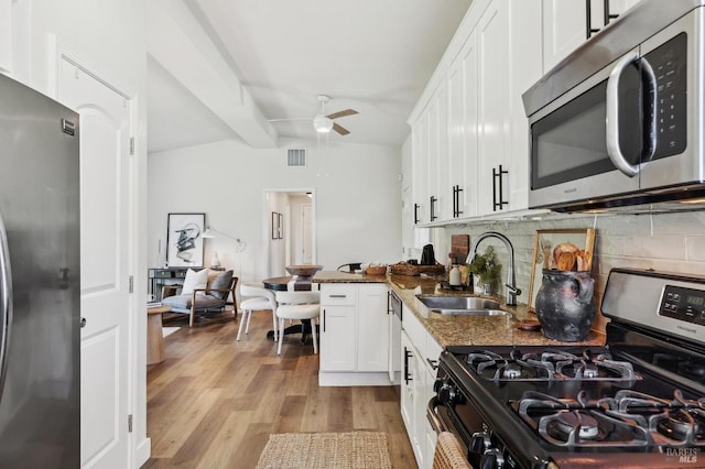 kitchen featuring ceiling fan, white cabinetry, a sink, backsplash, and stainless steel appliances