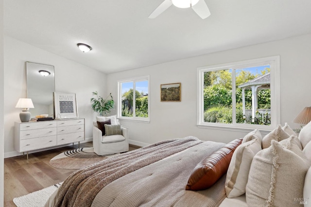 bedroom featuring baseboards, ceiling fan, wood finished floors, and vaulted ceiling
