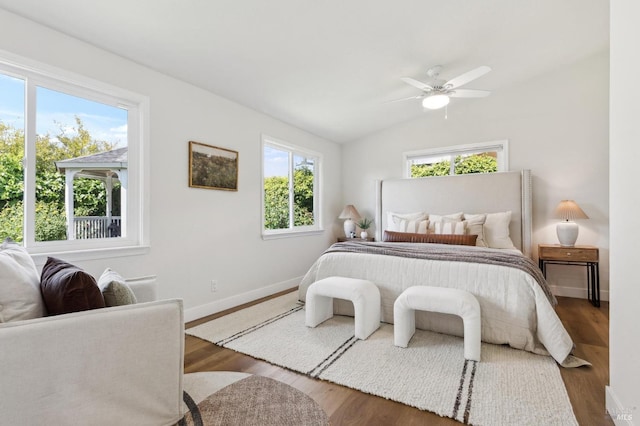 bedroom with baseboards, ceiling fan, wood finished floors, and vaulted ceiling