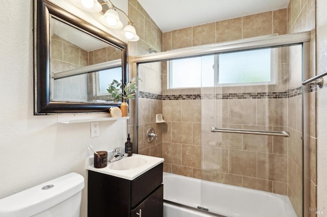 bathroom with plenty of natural light, combined bath / shower with glass door, toilet, and vanity