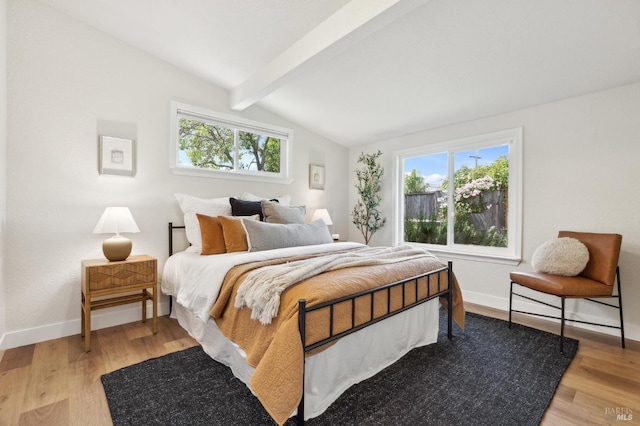 bedroom with baseboards, multiple windows, vaulted ceiling with beams, and wood finished floors