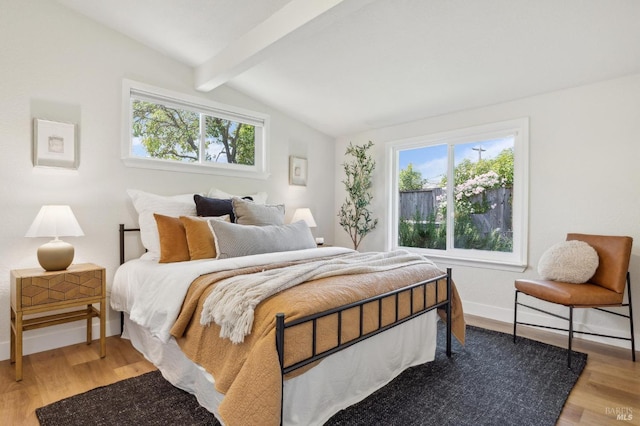 bedroom featuring baseboards, lofted ceiling with beams, multiple windows, and light wood-type flooring
