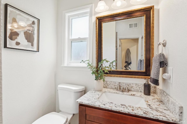 bathroom featuring vanity, toilet, and visible vents