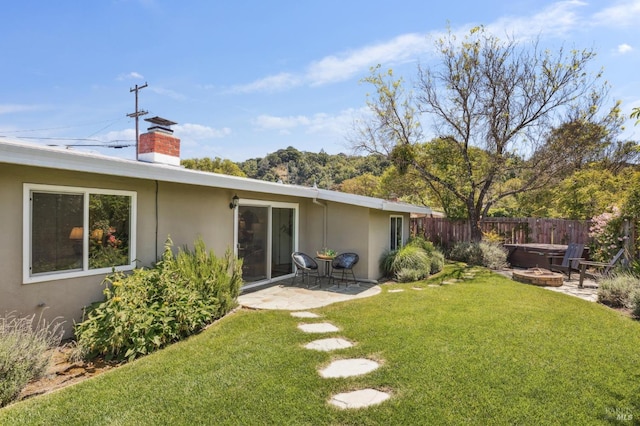 exterior space with a chimney, a lawn, a patio area, fence, and stucco siding
