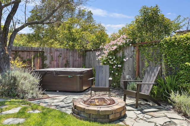 view of patio featuring a hot tub, fence, and an outdoor fire pit