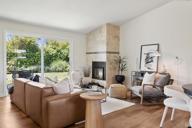 living area featuring vaulted ceiling, a tiled fireplace, and wood finished floors