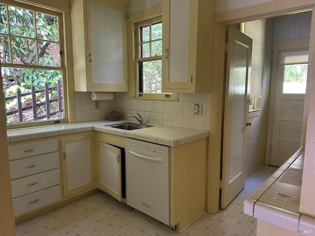 kitchen with a sink, tile counters, backsplash, and dishwasher