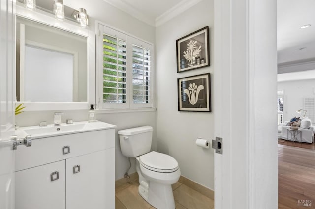 half bathroom with crown molding, toilet, baseboards, and vanity