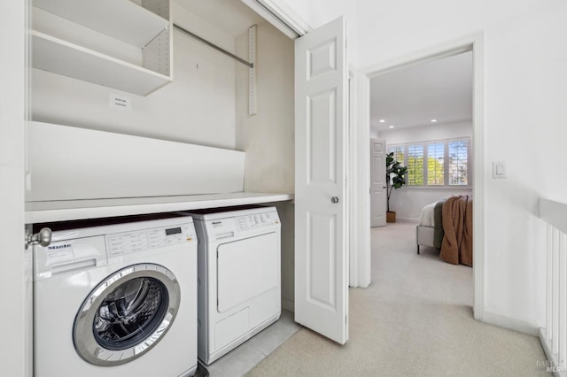 laundry area with washing machine and clothes dryer, laundry area, light carpet, and baseboards