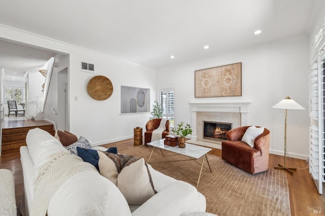 living area with recessed lighting, baseboards, wood finished floors, a high end fireplace, and visible vents