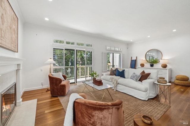 living room with a premium fireplace, baseboards, recessed lighting, and wood finished floors