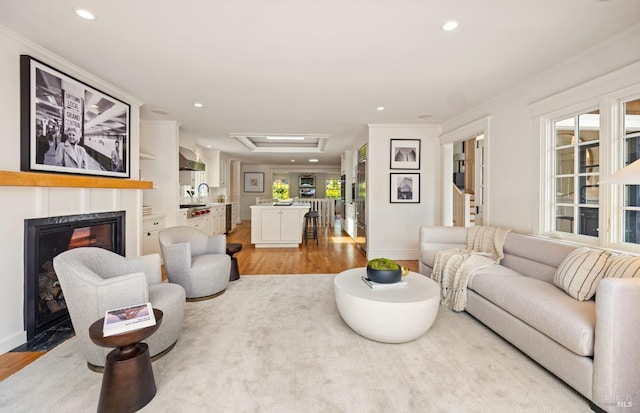 living room featuring recessed lighting, baseboards, a glass covered fireplace, and light wood-style floors