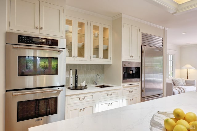 kitchen with crown molding, stainless steel appliances, white cabinetry, and a sink