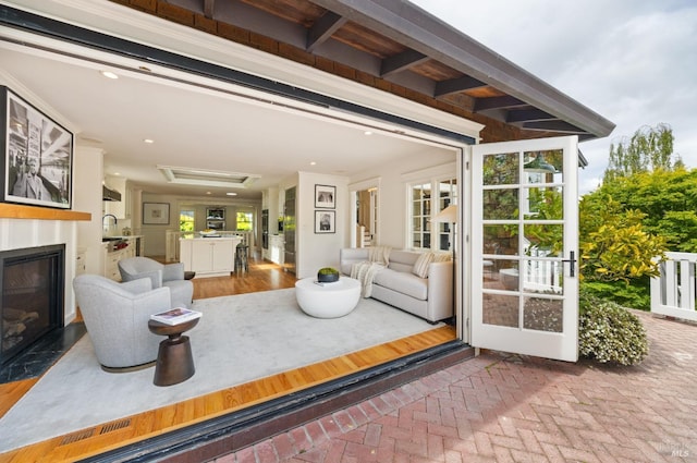 living room featuring recessed lighting, a glass covered fireplace, and brick floor