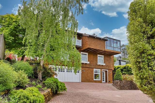 view of front facade with an attached garage, decorative driveway, and a balcony