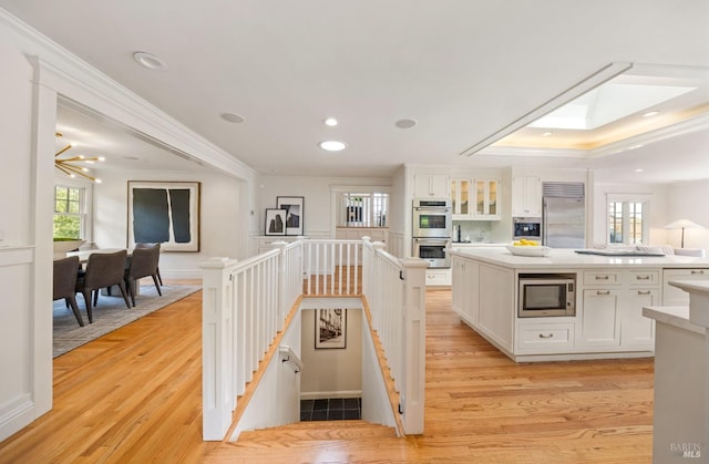 kitchen featuring built in appliances, a center island, light wood-style flooring, and white cabinetry