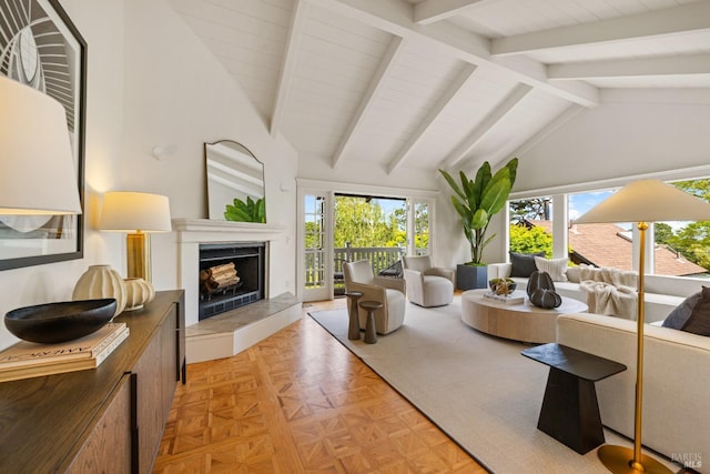 living area with high vaulted ceiling, beamed ceiling, a tile fireplace, and a wealth of natural light