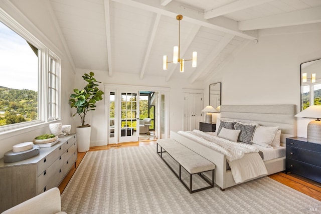 bedroom with lofted ceiling with beams, an inviting chandelier, multiple windows, and wood finished floors