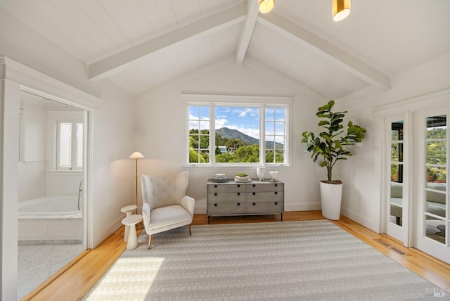 sitting room featuring vaulted ceiling with beams, baseboards, visible vents, and wood finished floors