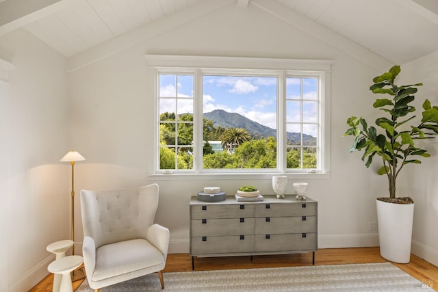 sitting room featuring baseboards, vaulted ceiling with beams, a mountain view, and wood finished floors