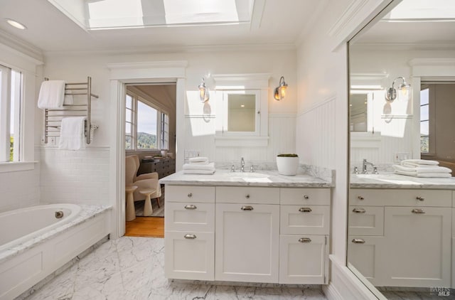 full bathroom featuring radiator, marble finish floor, two vanities, a wainscoted wall, and a sink