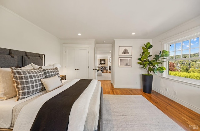 bedroom with baseboards, ornamental molding, recessed lighting, and light wood-style flooring