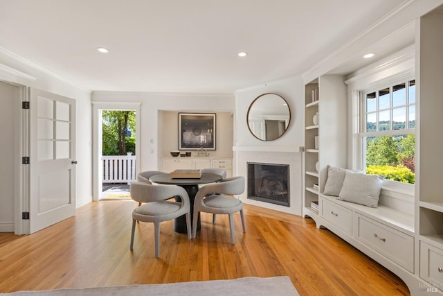 dining room featuring ornamental molding, recessed lighting, light wood-style flooring, and a tile fireplace