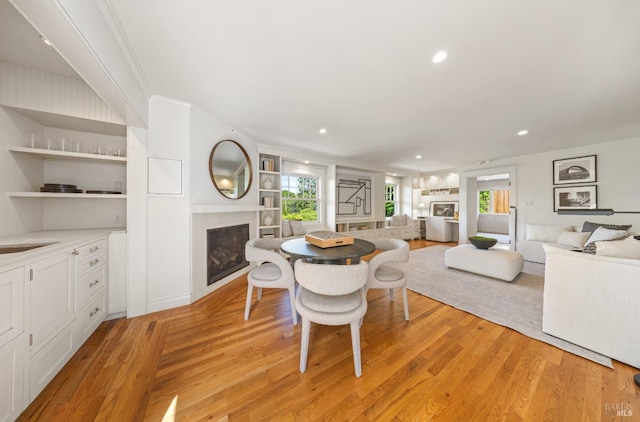 dining room with recessed lighting, light wood-style flooring, and a fireplace