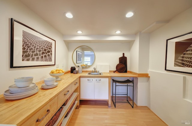 bar featuring light wood-type flooring, a sink, and recessed lighting