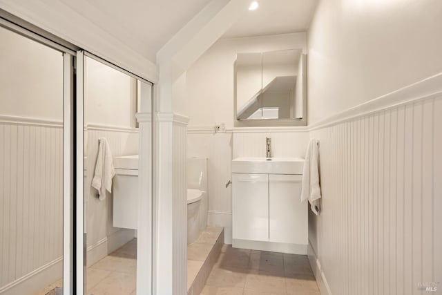 bathroom with vanity, tile patterned floors, a wainscoted wall, and toilet