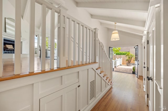 corridor with stairs, visible vents, vaulted ceiling with beams, and light wood-style floors