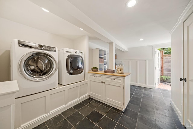 clothes washing area with a decorative wall, recessed lighting, cabinet space, and washer and clothes dryer